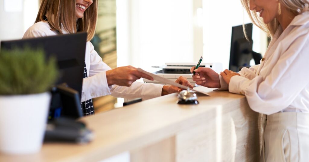 Receptionist assisting consumer at the front desk.